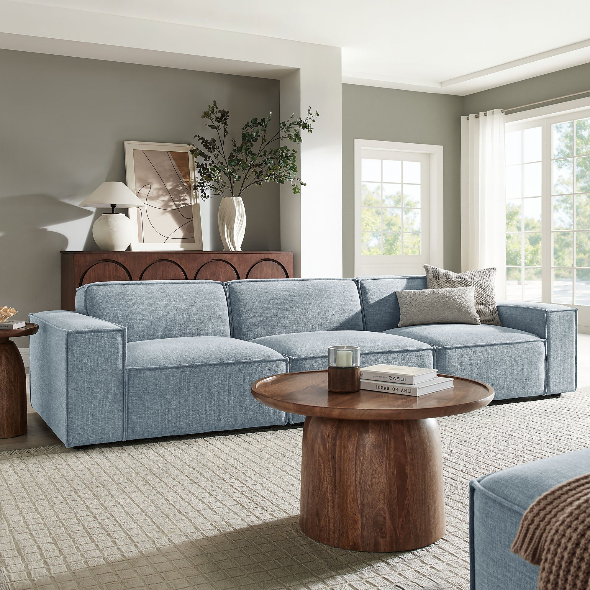 Modern living room with a blue sectional sofa, wooden coffee table, and decorative elements.