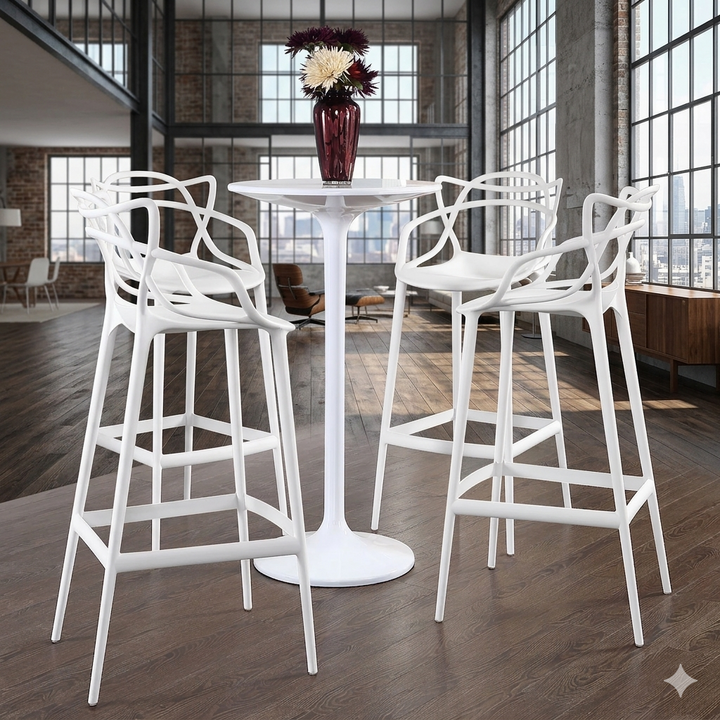 White bar stools around a round white table with a vase of flowers in a modern interior setting.