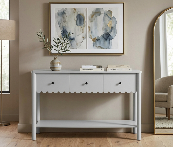 White console table with scalloped edge in a room with abstract art and decor.